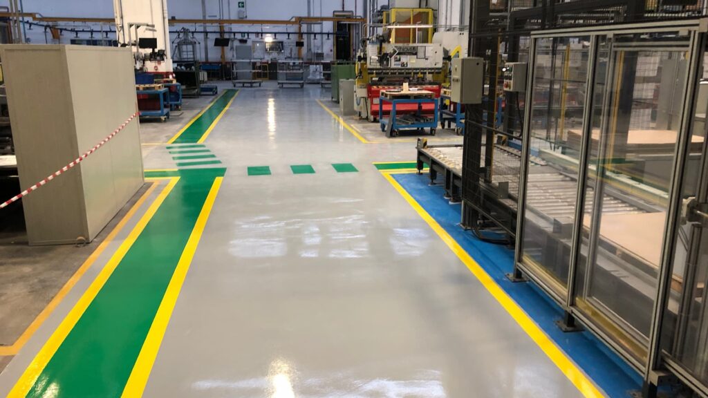 Pavimentazione industriale in resina per logistica con segnaletica orizzontale per la gestione dei flussi e corsie di sicurezza.